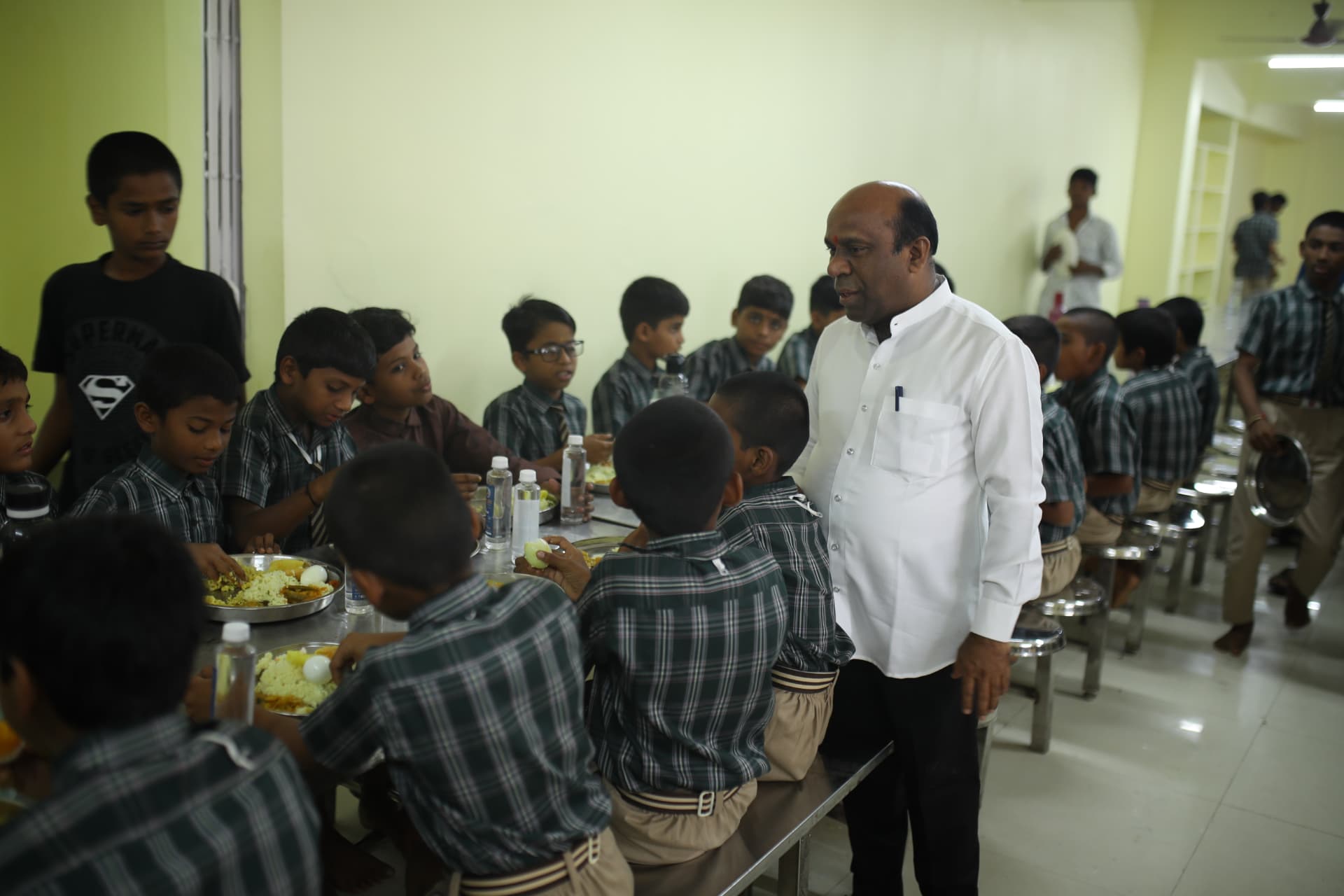 An adult visiting Aadarana children during lunch in the dining hall