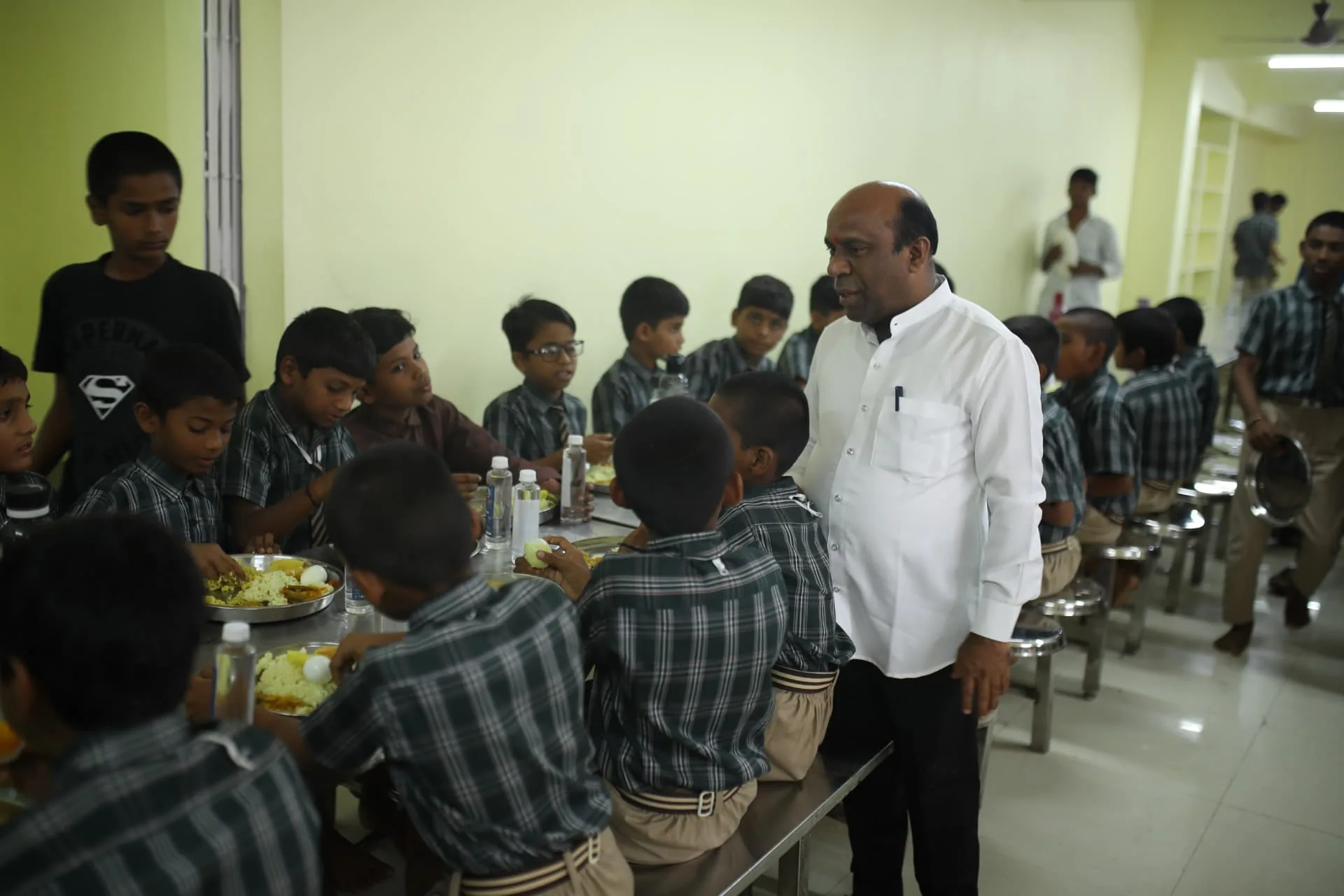 An adult visiting Aadarana children during lunch in the dining hall
